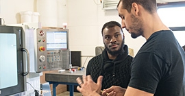 Two men talk in a lab with computers